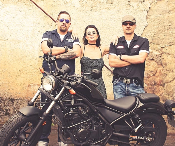 Drei Personen hinter einem Motorrad